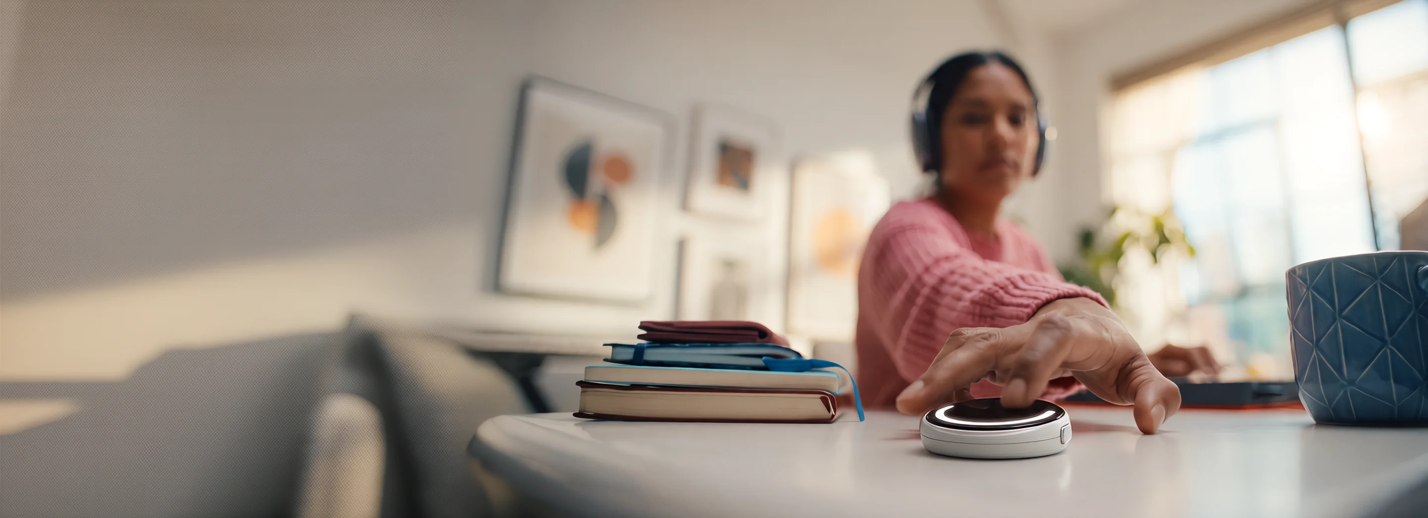 A woman reaching for her EgoClip on a desk at home